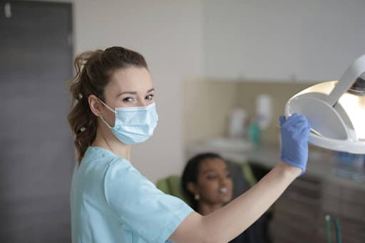 Dental assistant adjusting overhead dental exam light